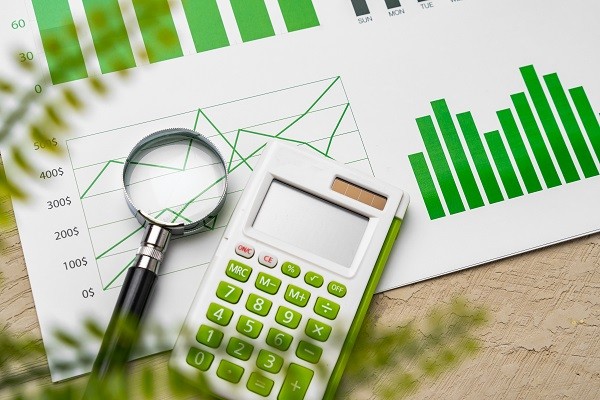 A magnifying glass and calculator on top of charts and diagrams