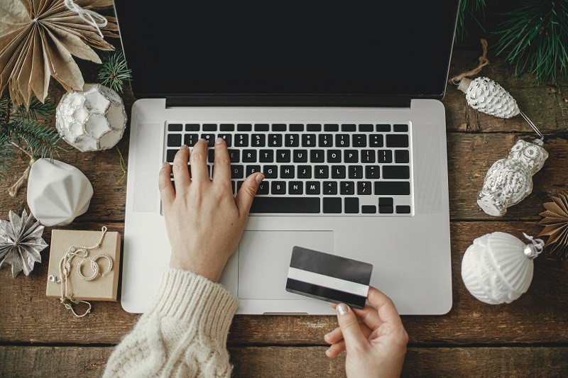 Hand holding a credit card and typing with the keyboard of a laptop