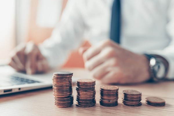 Stacks of coins on top of a table with laptop behind it