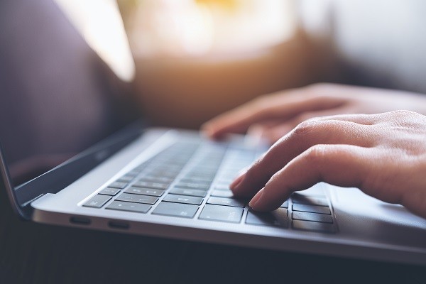 closeup of a person's hand typing with the laptop keyboard