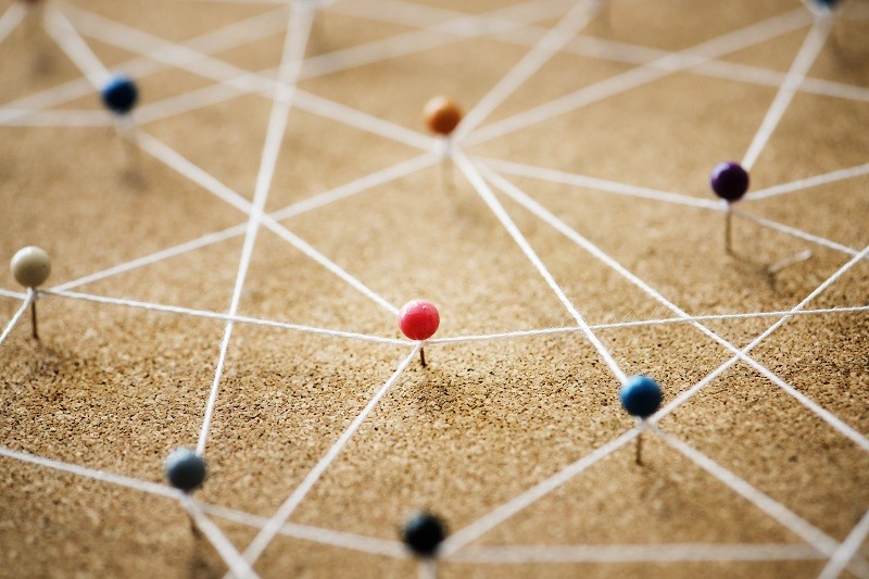 Push pins interconnected on cork message board