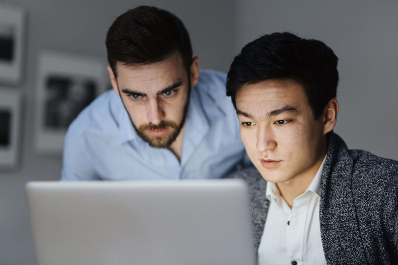 Two business professionals reviewing cybersecurity compliance information on a laptop.