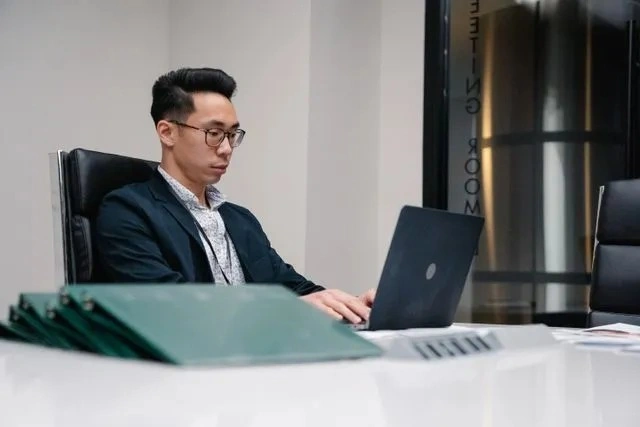 Corporate Compliance Officer Reviewing Generative AI Guidelines A corporate compliance officer reviewing PDPC generative AI guidelines on a laptop in a modern Singapore office.