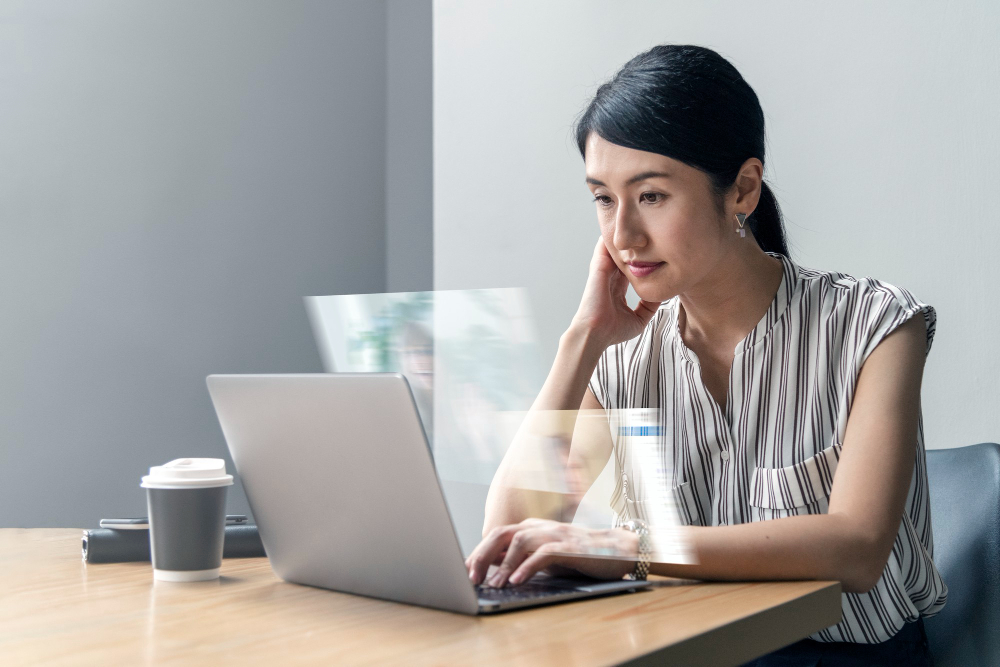 Financial compliance consultant working at a desk with a calculator and laptop, reviewing MAS licence variation documents.